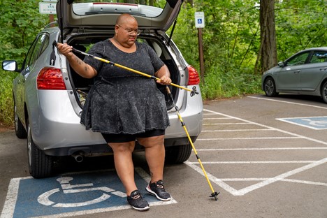 Woman standing near a car holding wakling sticks
